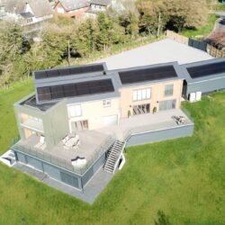 An aerial picture of a modern house with solar panels and air source heat pumps.