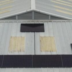 Aerial view of solar panels installed on a large industrial building roof.