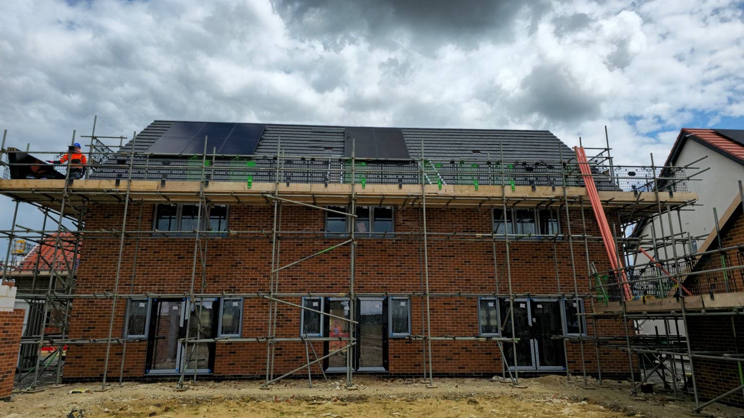 New construction house with solar panels and scaffolding installed on the roof.