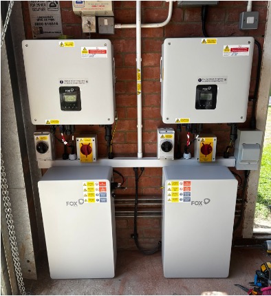 Two FOX-branded electrical control units and two battery storage units are mounted on a brick wall, with visible wiring and safety labels.